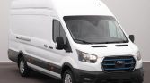 White Ford cargo van with high roof, black bumper, & side mirrors parked indoors, front grille visible.