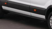 White van with black side panels and orange side marker lights along the lower door area. A running board is visible beneath the doors.