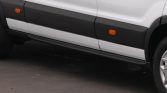 Side view of a white van with a black lower panel and orange side markers along the doors.
