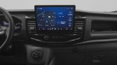 Dashboard of a vehicle with a large central touchscreen showing a navigation map and control widgets, flanked by air vents and climate controls, in a dark interior.