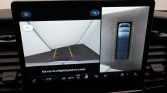 Infotainment screen showing rearview camera and bird’s-eye parking view with colored guide lines for parking assistance.