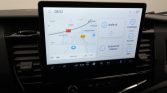 Infotainment-scherm in een auto: kaartweergave met route en snellekoppelingen ‘Audio uit’, ‘Verbind met telefoon’, ‘Instellingen’, ‘Functies’, ‘Apps’ aan de rechterkant (08:52, 25°C).