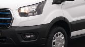 Front-left view of a white cargo van showing the headlight, blue-accent grille, and front wheel.