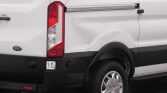 White Ford cargo van rear quarter with a dented side panel and black bumper, visible tail light and wheel.