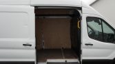 Open side door of a white cargo van showing a plywood-lined interior and empty rear cargo space under a raised threshold step