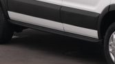 Side view of a white SUV with black rocker panels and a lower running board along the doors