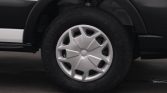 Close-up of a car wheel: black tire with a silver hubcap featuring geometric spokes