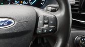Steering wheel with Ford emblem and multifunction controls on the right side, including OK button and navigation pad.