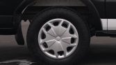 Close-up of a car wheel with a silver hubcap and black tire, partially under the fender of a two-tone vehicle.