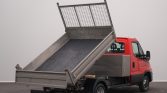 Red dump truck with its metal cargo bed raised at an angle, ready to unload material