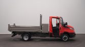 Red flatbed truck with cab door open, parked indoors, showing cargo bed and utility equipment behind the cab