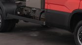 Red semi-truck with a long side underride guard extending along the lower side for protection