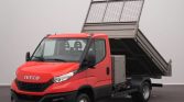 Red Iveco tipper truck with raised dumping bed, parked indoors; front cab visible and cargo bed tilted for dumping.