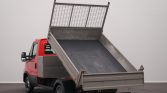 Red and gray dump truck with its bed raised, ready to unload contents from the back. (informative)