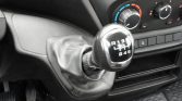 Manual gear shifter in a car interior with surrounding climate controls and center console visible to the right