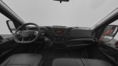 Interior view of a left-hand-drive vehicle: steering wheel, center console with radio and climate controls, manual gear shift, and front seats seen from the passenger side.