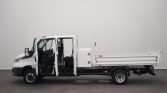 White flatbed utility truck with both front doors open, showing cab interior and side storage box in a studio setting