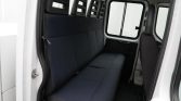 Interior of a white van showing a dark blue fabric bench seat with three headrests and windows on the side.