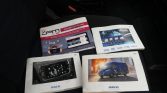 Car manuals and brochures (Iveco and JPM Group) laid on a car seat, showing vehicle info and apps.