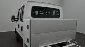 Rear-left view of a white utility van featuring a large metallic rear cargo box and black mirrors/trim, indoors.