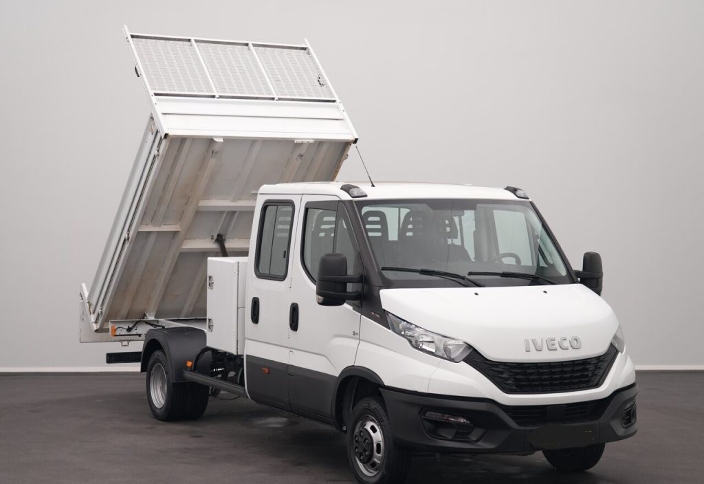 White Iveco dump truck with its cargo bed raised for dumping in a studio setting