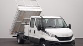 White Iveco dump truck with its cargo bed raised for dumping in a studio setting