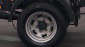 Wheel of a commercial truck with a silver steel rim and black tire mounted on the axle