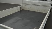 Open truck bed with gray floor and white side rails, cargo area shows rust marks and a metal grid partition at the front.