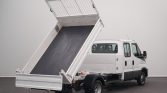 White utility van with its cargo bed raised in a dumping position, ready to unload material.
