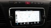 In-car touchscreen navigation display showing a map with a blue location marker on a car dashboard