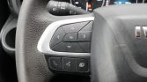 Close-up of a car steering wheel's left control pad with directional arrows and an OK button, plus phone and voice/mode buttons below