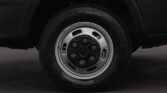 Close-up of a black steel car wheel with six lug nuts and a silver rim on a dark-tread tire.