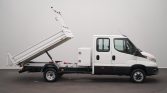 White flatbed dump truck with its cargo bed tilted upward for unloading, viewed from the side.