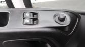 Driver-side interior door panel with two window control switches and a circular power mirror adjustment knob at right side