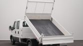 White cab-and-chassis dump truck with its cargo bed raised in a tipping position, ready to unload