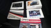 Assorted automotive brochures and catalogs spread on a car seat, including JPM Group and Iveco branding with images of a van and dashboard.