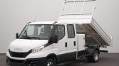 White Iveco utility truck with a raised tilting dump bed and mesh tailgate, viewed in a studio setting