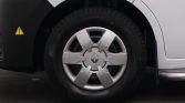 Close-up of a car wheel with a Renault hubcap and tire, showing the front fender and a yellow high-voltage warning sticker nearby.
