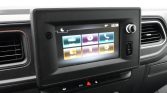 In-car touchscreen infotainment system displaying six colorful app icons (media, navigation, phone, settings) in a vehicle dashboard setting.