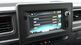 Car stereo touchscreen in a vehicle showing radio presets and frequencies (FM) on the display panel.