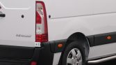 White Renault van rear with taillight, bumper, and wheel visible; side panel shows black trim and orange reflectors.