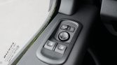 Interior car door panel showing power window switches and a circular side‑mirror adjustment pad with directional arrows
