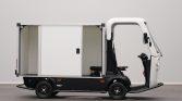 Side view of a small urban delivery truck with a large open cargo compartment behind the cab.
