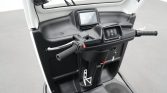 Handlebar and control cluster of a scooter with grips, brake levers, and ignition area inside the front panel.