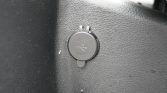 USB charging port cover on a textured car interior panel, shown in close-up