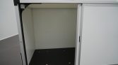 Open gray metal cabinet with empty interior and a black perforated floor panel.