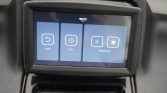 In-car touchscreen with four blue control tiles: Home, Time, and two Brightness icons on a car dashboard.