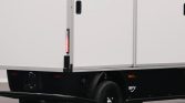 Rear corner of a white utility trailer with a vertical red taillight, black undercarriage, and a visible wheel.