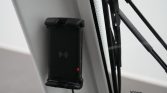 Black wireless charging device mounted on a grey panel, featuring a wireless-symbol icon and a small red status LED.