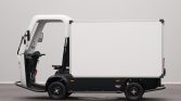 Side view of a small electric delivery truck with a white cargo box on a black chassis and an open driver's area